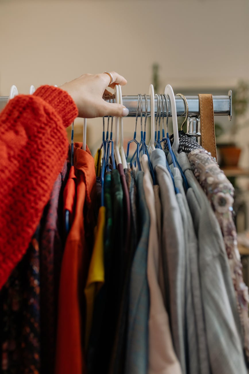 person holding clothes hanger with clothes Show what the website is about, reselling clothes.